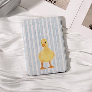 May include: A rectangular phone case featuring a yellow duckling illustration on a light blue and white striped background. The duckling is centered on the case, with its orange feet and beak adding contrast. The case has a smooth finish.