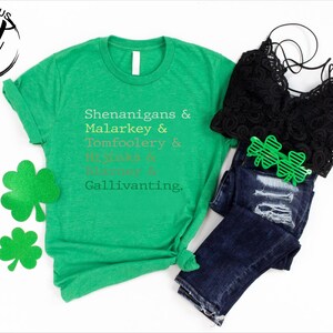 May include: A green t-shirt with the words "Shenanigans & Malarkey & Tomfoolery & Hijinks & Blarney & Gallivanting" printed on it. The image also includes a black lace top, blue jeans, and green shamrock-shaped sunglasses and decorations.