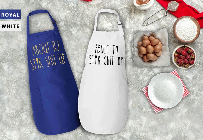 May include: Two kitchen aprons, one royal blue and one white, with the text "About to Stir Shit Up" printed on them.