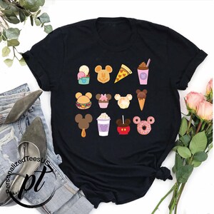 May include: Black t-shirt with a graphic of various Disney food items, including Mickey Mouse ears, ice cream, popcorn, and a donut. Each food item has a Mickey Mouse head on it.