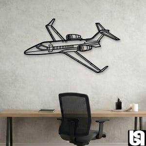 May include: Black metal wall art depicting a detailed outline of a private jet. The artwork features wings, engines, and a fuselage, mounted on a textured, light-colored wall. The jet is positioned above a desk and office chair.