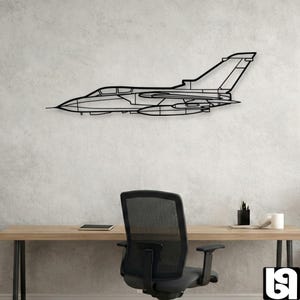 Pode incluir: Uma peça de arte de parede em metal preto com o formato de um avião de caça de perfil. O design apresenta um contorno linear limpo da aeronave, incluindo a cabine, as asas, a barbatana da cauda e os tanques de combustível sob as asas.