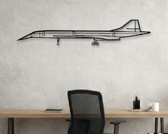 May include: A black metal wall art piece of the Concorde supersonic jet. The artwork is a detailed outline of the aircraft, including wings, tail, and landing gear. The piece is mounted on a light grey wall, above a desk and chair.