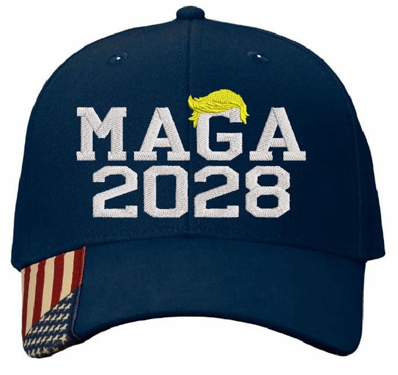 May include: A navy blue baseball cap with a white American flag on the side. The front of the cap has white embroidery that says "MAGA 2028" with a yellow silhouette of a hairstyle above the text.