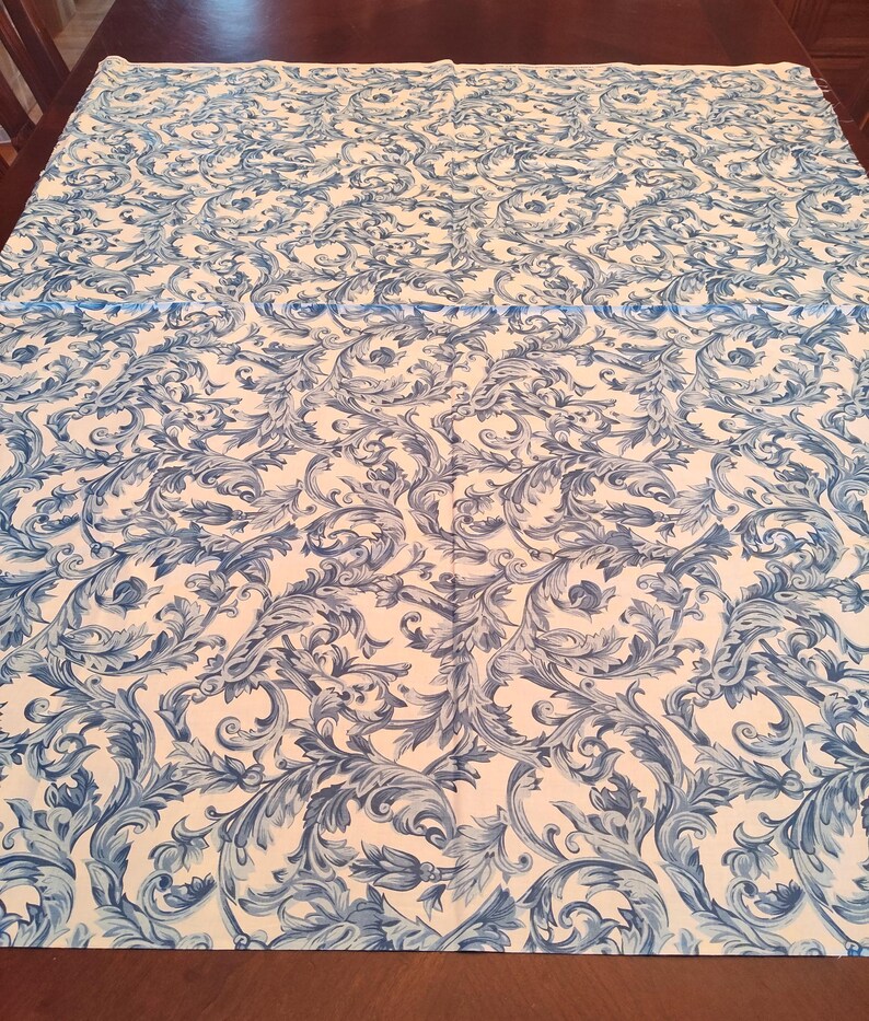 K&ouml;nnte beinhalten: Wei&szlig;er Stoff mit einem blauen und wei&szlig;en Blumenmuster. Das Muster zeigt komplizierte Wirbel und Bl&auml;tter.