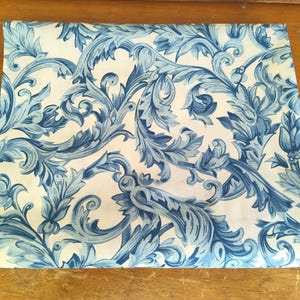 K&ouml;nnte beinhalten: Wei&szlig;er Stoff mit einem blauen Blumenmuster. Das Muster zeigt komplizierte Wirbel und Bl&auml;tter.