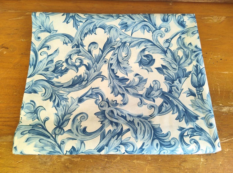 K&ouml;nnte beinhalten: Wei&szlig;er Stoff mit einem blauen Blumenmuster. Das Muster zeigt komplizierte Wirbel und Bl&auml;tter.