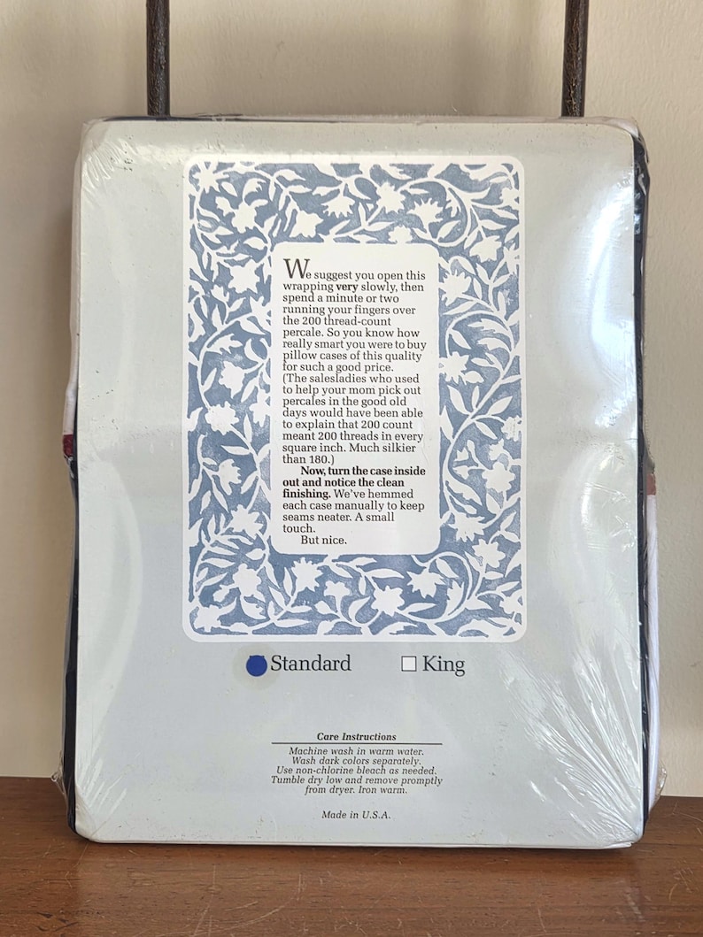 May include: A packaged pillowcase set with a light blue and white floral design. The packaging includes text describing the percale fabric and care instructions. The set is available in standard and king sizes.