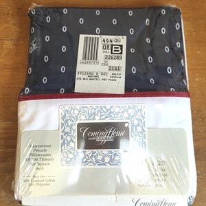 May include: A packaged set of Coming Home brand pillowcases. The top of the package is navy blue with white oval patterns. The bottom is white with a red stripe. The package includes two percale pillowcases made of 50% combed cotton and 50% polyester.