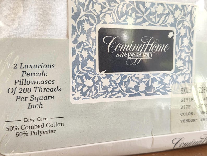 May include: White percale pillowcases from Lands' End, featuring a floral design and the text "Coming Home." The packaging indicates 200 threads per square inch, 50% combed cotton, and 50% polyester. The label has a blue and white floral border.