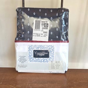 May include: A packaged bedding set featuring a navy blue top sheet with white oval patterns and a white bottom sheet. The packaging includes a label with product information and the brand name "Coming Home". The set includes two percale pillowcases.