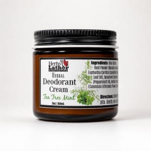 May include: An 88 ml amber glass jar of Herbs n Lather Herbal Deodorant Cream in Tea Tree Mint scent. The white label features black text, a green botanical illustration, and lists ingredients including shea butter and essential oils.