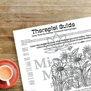 Op de afbeelding: Een Therapeuten Gids getiteld "Color My Feelings" met bloemen kleurplaten. Een kopje koffie staat op een rode schotel. De gids is ontworpen om emoties uit te drukken en te verkennen met behulp van kleur.