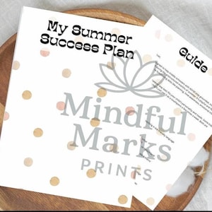 May include: A white printed guide and plan titled "My Summer Success Plan" and "Guide" with a floral logo and the text "Mindful Marks Prints" on a wooden plate with a white background. The plan has peach and gold polka dots.