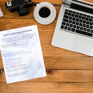 May include: A workspace scene with a laptop, coffee, a camera, and a document titled "Exploring Alternative Outcomes." A black pen and a white mouse are on the wooden surface.