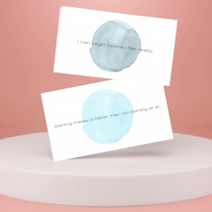 May include: Two white cards with blue watercolor circles and inspirational quotes. The top card reads "I can begin before I feel ready." The bottom card reads "Starting messy is better than not starting at all."