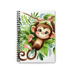 Puede incluir: Cuaderno de espiral con una ilustración en acuarela de un mono marrón sonriente colgado de una cuerda entre hojas verdes. El cuaderno tiene una cubierta blanca y una encuadernación en espiral negra.
