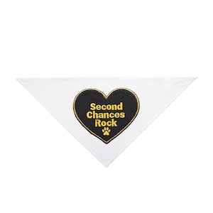 May include: White triangular pet bandana with a black heart-shaped patch. The patch has gold text that reads "Second Chances Rock" and a gold paw print. The bandana is likely for a dog or cat.