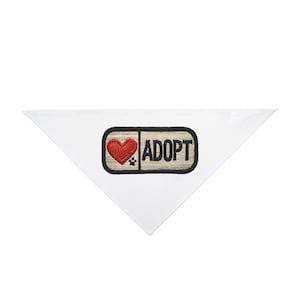 May include: White triangular pet bandana with a rectangular patch. The patch features a red heart, a paw print, and the word "ADOPT" in black letters. The patch has a tan background and a black border.