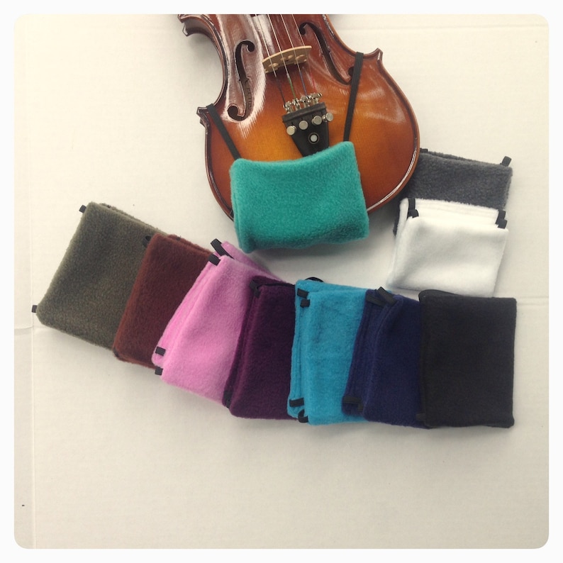 May include: A set of ten colorful fleece violin shoulder rests in various colors, including green, pink, blue, brown, and black. The shoulder rests are designed to provide comfort and support for violin players.
