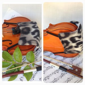 Puede incluir: Un viol&iacute;n con un reposabrazos de patr&oacute;n blanco y negro y un arco de viol&iacute;n marr&oacute;n sobre partituras.