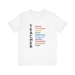Peut inclure: T-shirt blanc avec le mot "TEACHER" imprimé verticalement en noir sur le côté gauche. Le t-shirt répertorie également diverses professions en différentes couleurs, notamment Infirmière, Conseiller, Coach, Réparateur, Détective, Magicien, etc.