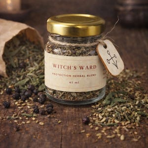May include: A small glass jar with a gold lid, labeled "Witch's Ward Protection Herbal Blend, 41 ml." The jar is tied with twine and has a small tag. The jar is surrounded by dried herbs and berries on a wooden surface.
