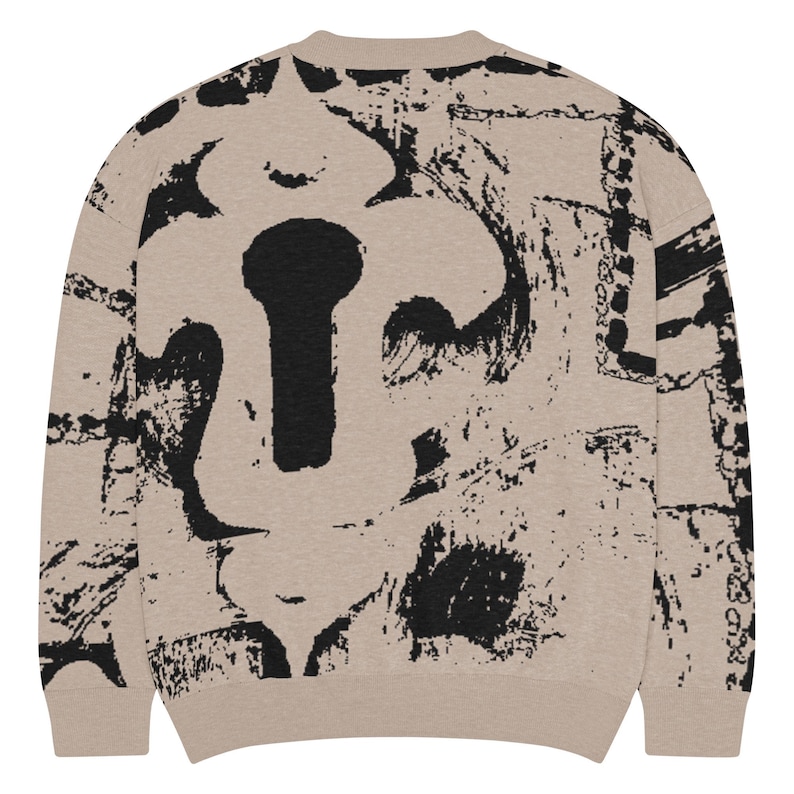May include: A beige sweatshirt featuring a large black keyhole design. The keyhole is surrounded by abstract black brushstrokes. The sweatshirt has a crew neck and long sleeves. The design covers the front and back.