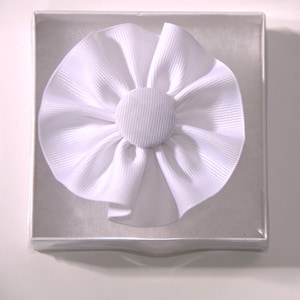 May include: A white fabric flower with a white button center in a white box.
