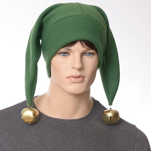 May include: A green fleece elf hat with long, pointed ears and gold bells attached to the ends.