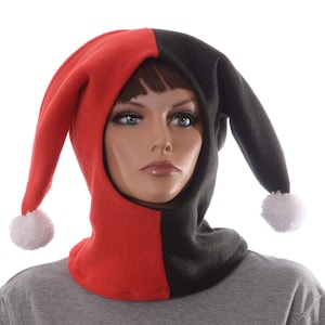 May include: A red and black fleece balaclava with white pom-poms on the ends of the two long ear flaps. The balaclava is pulled up over the head of a mannequin.