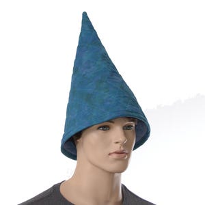 May include: A tall, pointed cone-shaped hat in a mottled teal and blue fabric. The hat features a quilted diamond pattern across its surface and a wide, slightly flared brim that curves downward around the base of the head covering.