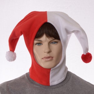 May include: A red and white jester hood with a pom-pom at the end of each point. The hood is split down the middle, with one side red and the other white. The hood is worn by a mannequin.