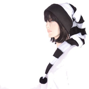 May include: Black and white striped beanie with a long, flowing scarf. The beanie has a black pom-pom on top.
