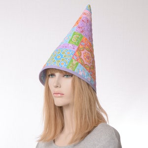 May include: A tall, pointed hat with a patchwork design featuring various shades of blue, green, pink, and orange. The hat has a purple trim around the brim.