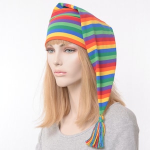 May include: A colorful rainbow striped sleep hat with a long, pointed end and a tassel. The hat is made of soft fabric and features horizontal stripes in various colors, including red, orange, yellow, green, blue, and purple.