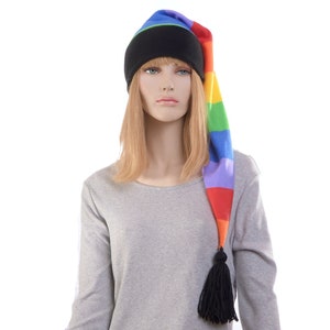 May include: A grey long-sleeved shirt with a rainbow striped beanie with a black tassel. The beanie has a black brim and a blue, green, yellow, orange, red, and purple striped design.