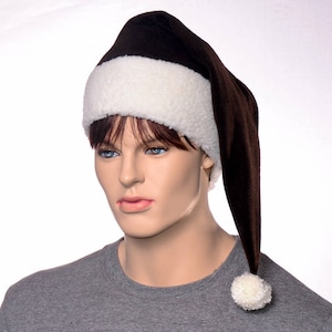 May include: A brown Santa hat with a white fluffy trim and a white pom-pom. The hat is worn by a mannequin. The hat is made of a soft material and is designed to be worn during the Christmas holiday season.