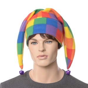 May include: A colorful jester hat with a checkered pattern in rainbow colors. The hat has three long, pointed tips and small purple bells at the ends. The hat is worn by a mannequin.