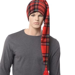 May include: A red tartan nightcap with a long, pointed tail and a red tassel. The hat features a classic plaid pattern in red, black, yellow, and blue. The hat is made of a soft fabric.