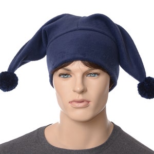 May include: A navy blue jester hat with long, pointed ends and a dark blue pom-pom at the end of each point. The hat is made of a soft fabric and is displayed on a mannequin. The hat is a costume accessory.