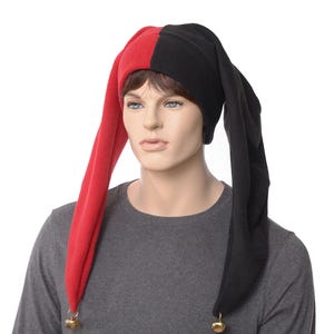 May include: A red and black jester hat with long, pointed ends. The hat has a bell at the end of each point. The hat is worn by a mannequin wearing a gray long-sleeve shirt.