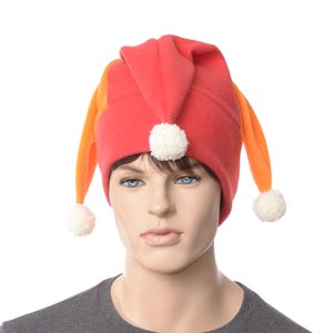 May include: A red and orange fleece jester hat with white pom-poms on the ends of the hat's points.