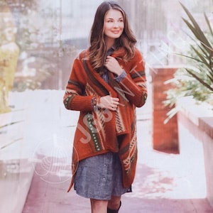 Könnte beinhalten: Eine langärmelige, vorne offene Strickjacke in gebranntem Orange mit einem mehrfarbigen geometrischen Muster an den Kanten und Ärmeln. Das Strickkleidungsstück wird über einem grauen Hemd mit Knopfleiste getragen und wirkt strukturiert.