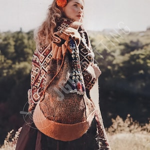 May include: A brown knitted shoulder bag with a rounded base and a decorative beaded tassel. The bag is made of a textured, woven material and has a contrasting orange-brown trim. The person in the image is wearing a patterned shawl.