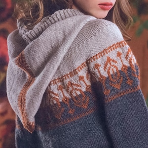 May include: A knitted hooded sweater featuring a color-blocked design with a light gray upper section, a dark gray lower section, and a band of intricate geometric patterns in rust orange and white across the chest and the hood trim.
