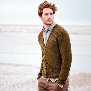 May include: A textured olive green knit cardigan with a V-neckline and dark buttons, worn over a grey and white plaid collared shirt paired with brown trousers. The knit fabric features a visible wool-like texture with ribbed cuffs and hem.
