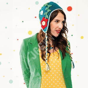 May include: A teal crochet hat with a floral design, featuring a red flower and white accents. The hat has long braided ties with yellow and teal details. The hat is part of a collection of handmade accessories.