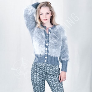 May include: A woman wearing a gray, fluffy cardigan with a button-up front and long sleeves. The cardigan is paired with patterned pants in shades of gray and blue. The outfit is a cozy and stylish ensemble.