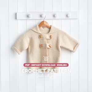 May include: A cream-coloured crochet cardigan with long sleeves, a wide collar, and two wooden toggle closures on the front. The image includes text that reads: PDF INSTANT DOWNLOAD ENGLISH CROCHET PATTERN Create with joy.